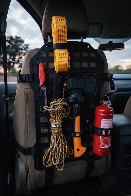 MOLLE panel on a car seat back holding rope, an axe and a fire extinguisher